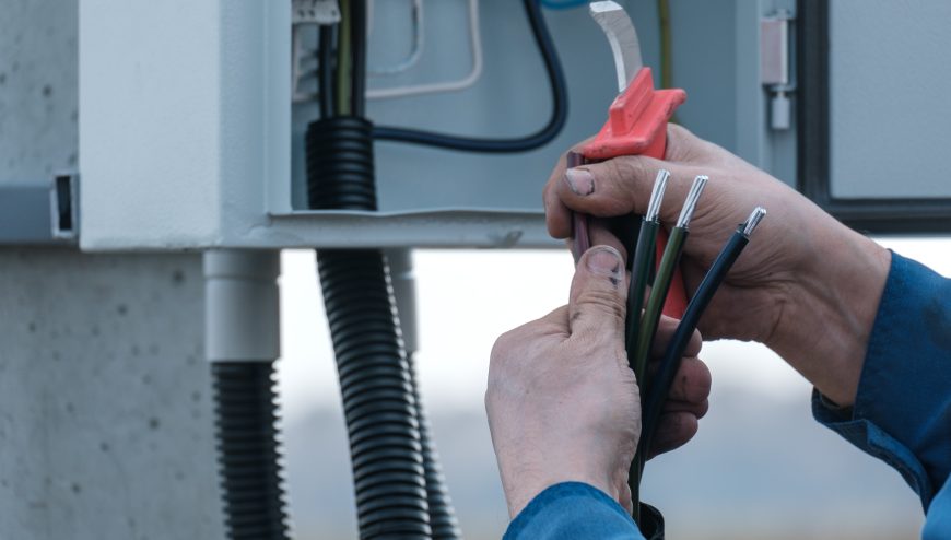 Master electrician cleans the insulation from the wires. installation of an electric shield. electrician's hands with wires close-up